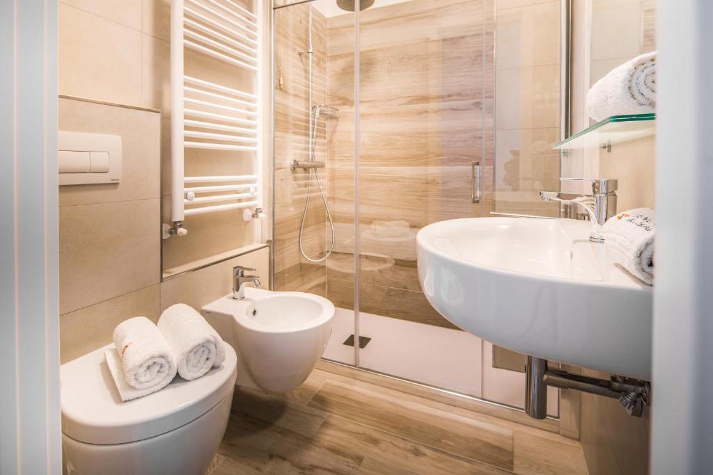une salle de bain avec un lavabo, des toilettes et un miroir dans l'établissement Hotel Bologna, à Lignano Sabbiadoro