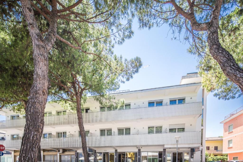 un immeuble de bureaux avec des arbres devant dans l'établissement Hotel Bologna, à Lignano Sabbiadoro