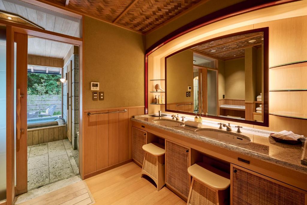 une salle de bain avec un lavabo et un grand miroir dans l'établissement Akazawa Geihinkan, à Itō