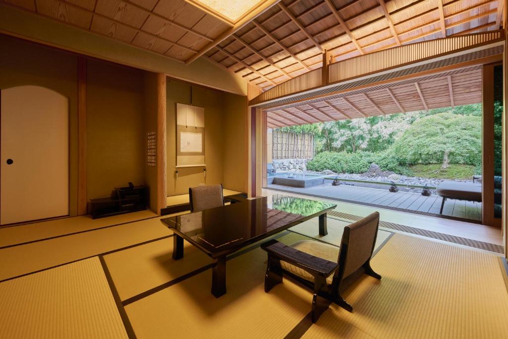 une salle à manger avec une table et des chaises et une grande fenêtre dans l'établissement Akazawa Geihinkan, à Itō