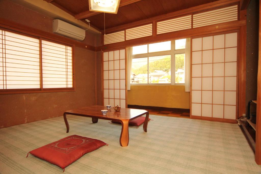 Cette chambre comprend une table et un tapis rouge. dans l'établissement Minshuku Miyama, à Yamanouchi