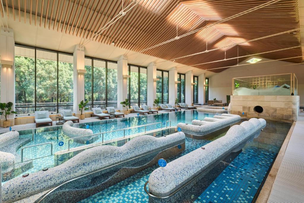 une grande piscine avec des chaises dans un bâtiment dans l'établissement Akazawa Geihinkan, à Itō