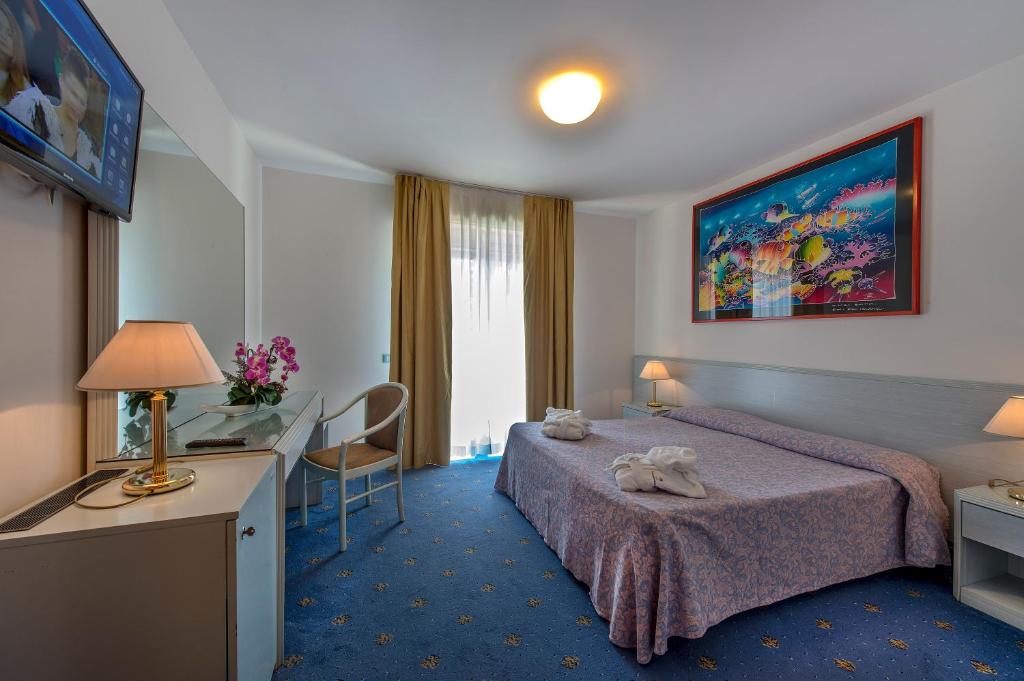 une chambre d'hôtel avec un lit et un bureau dans l'établissement Hotel Meridianus, à Lignano Sabbiadoro