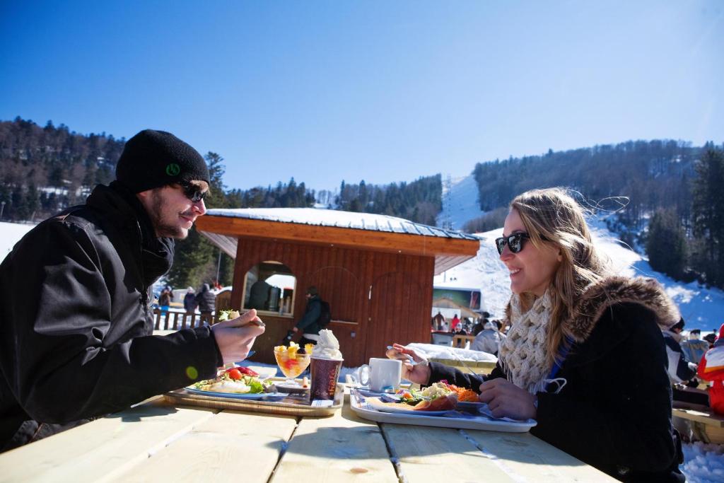 un homme et une femme assis à une table en train de manger dans l'établissement Résidence Les Grandes Feignes, à La Bresse