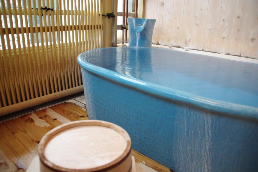 Cette chambre dispose de parquet et d'une baignoire bleue. dans l'établissement Asanoya, à Yumura