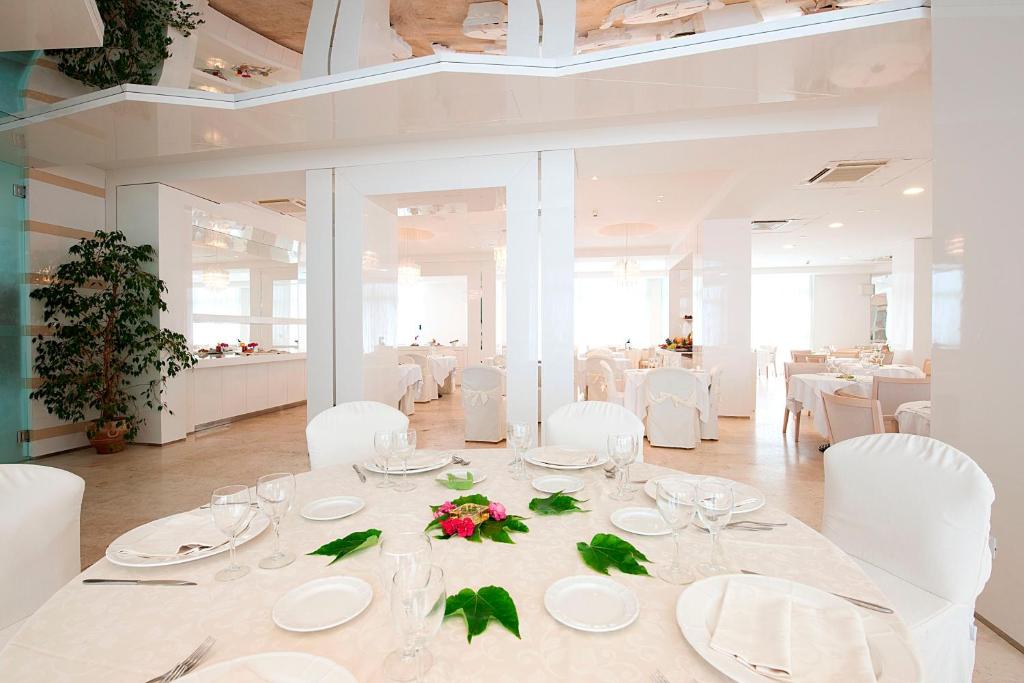 une salle à manger avec une table blanche et des chaises blanches dans l'établissement Hotel Excelsior, à Vasto 73 autres photos