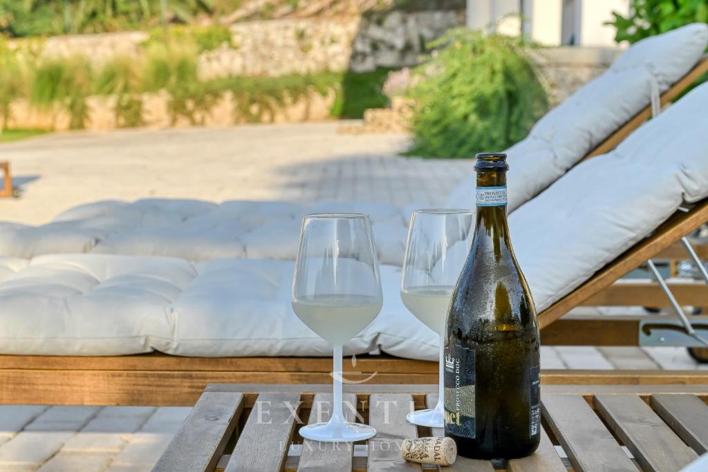 une bouteille de vin et deux verres sur une table dans l'établissement Luxury villa siracusa, à Syracuse