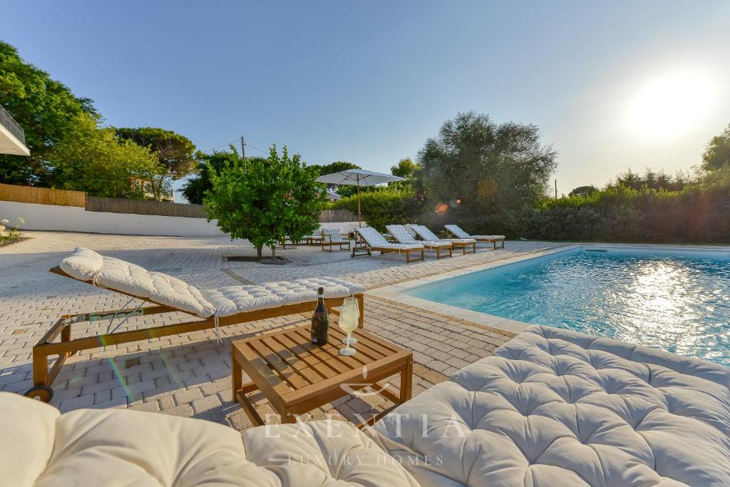 une piscine avec des chaises longues et un lit à côté dans l'établissement Luxury villa siracusa, à Syracuse