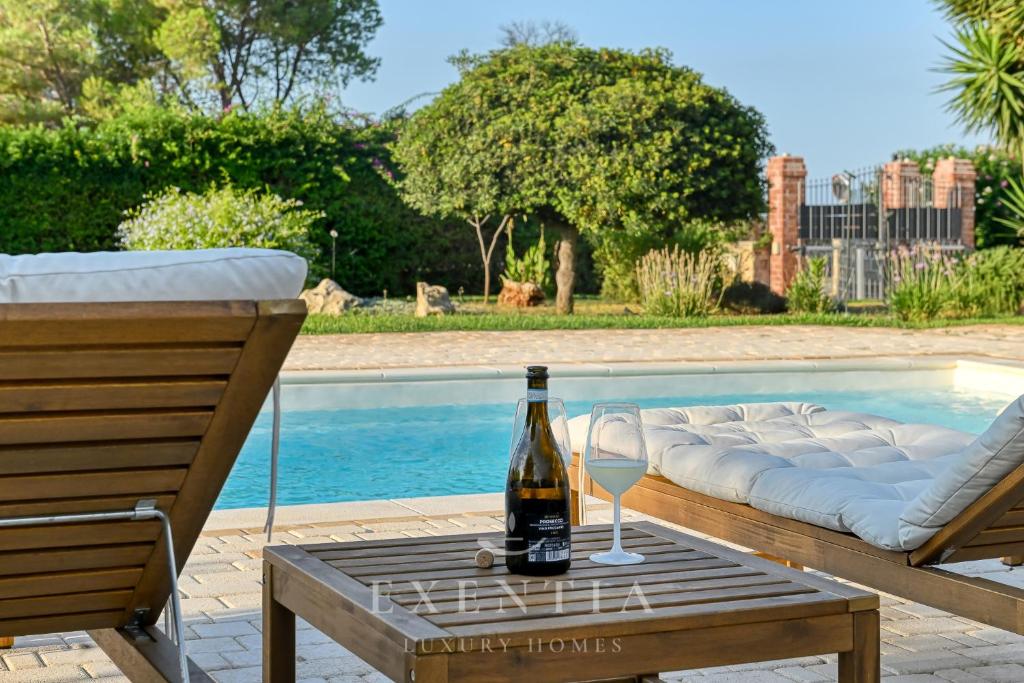 - une bouteille de vin sur une table près de la piscine dans l'établissement Luxury villa siracusa, à Syracuse