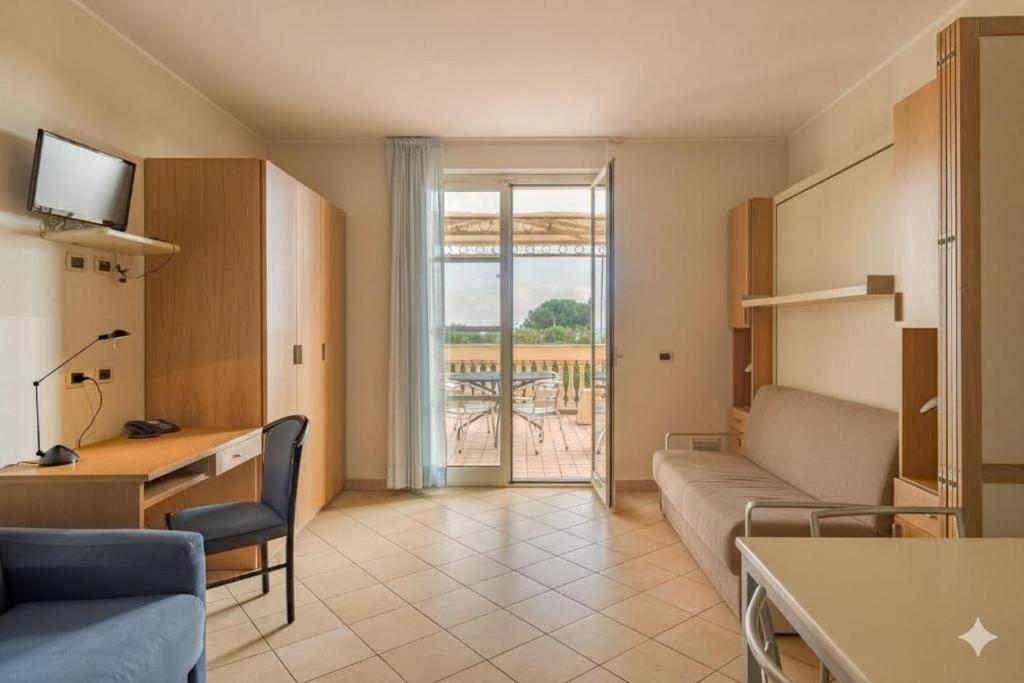 un salon avec un canapé, un bureau et une fenêtre dans l'établissement Residenza al Porto, à Spotorno