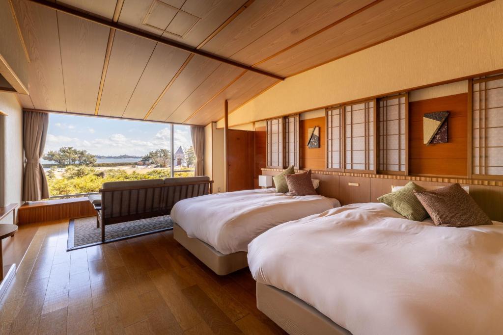deux lits dans une chambre avec une grande fenêtre dans l'établissement Matsushima Ichinobo, à Matsushima