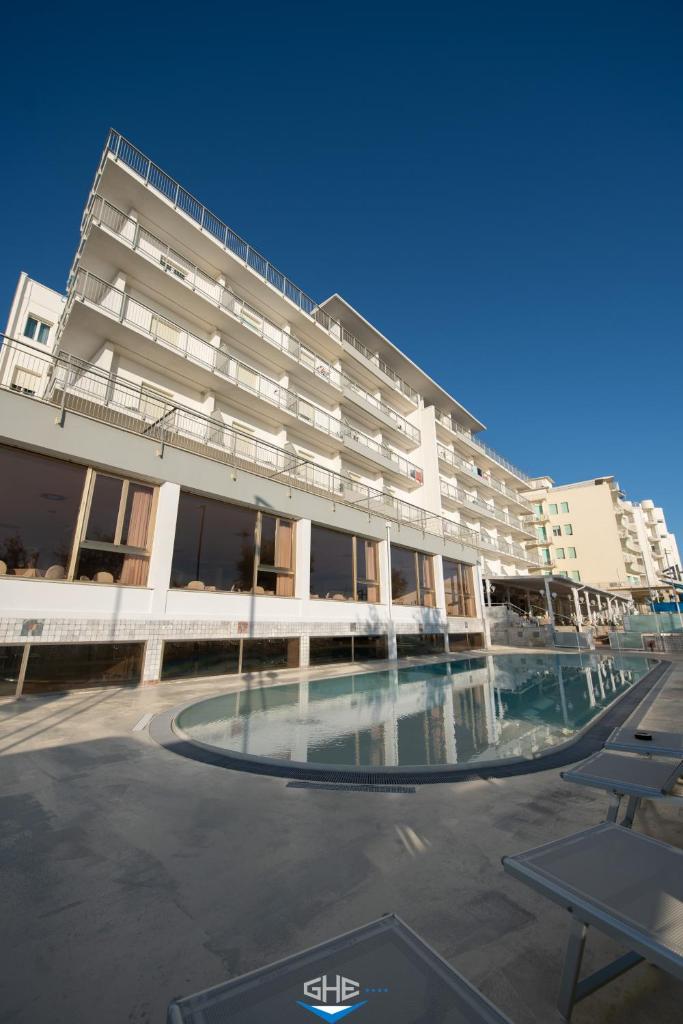 un grand bâtiment avec une piscine devant dans l'établissement Grand Hotel Excelsior, à Senigallia