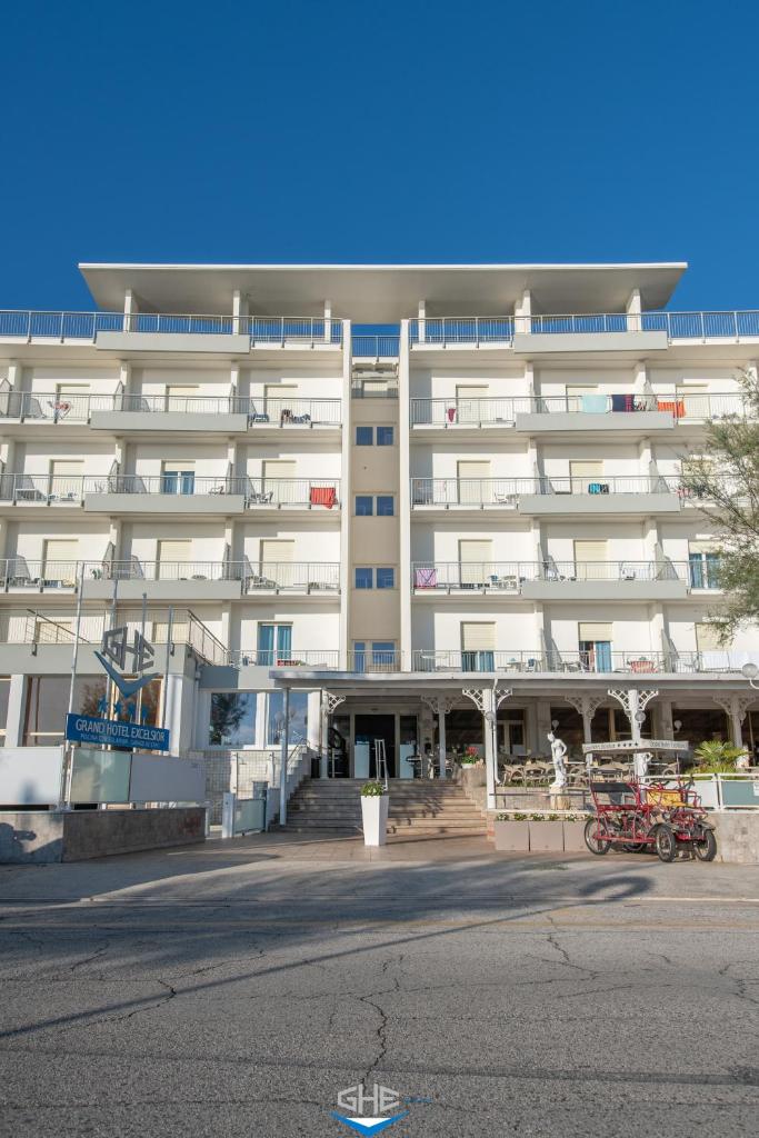 un grand bâtiment blanc avec un parking en face de celui-ci dans l'établissement Grand Hotel Excelsior, à Senigallia