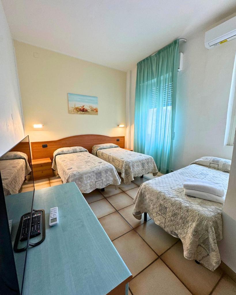 une chambre d'hôtel avec trois lits et une table dans l'établissement Hotel Valente, à Ortona