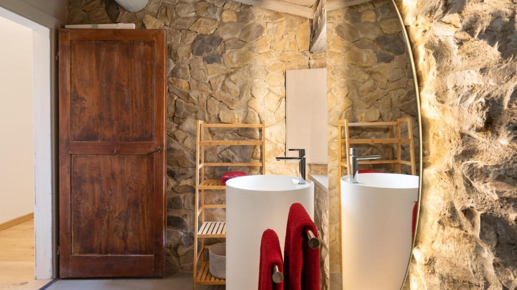 La salle de bains est pourvue de 2 lavabos et d'un mur en pierre. dans l'établissement TERRA DI SIENA 14, Emma Villas, à Castelnuovo Berardenga
