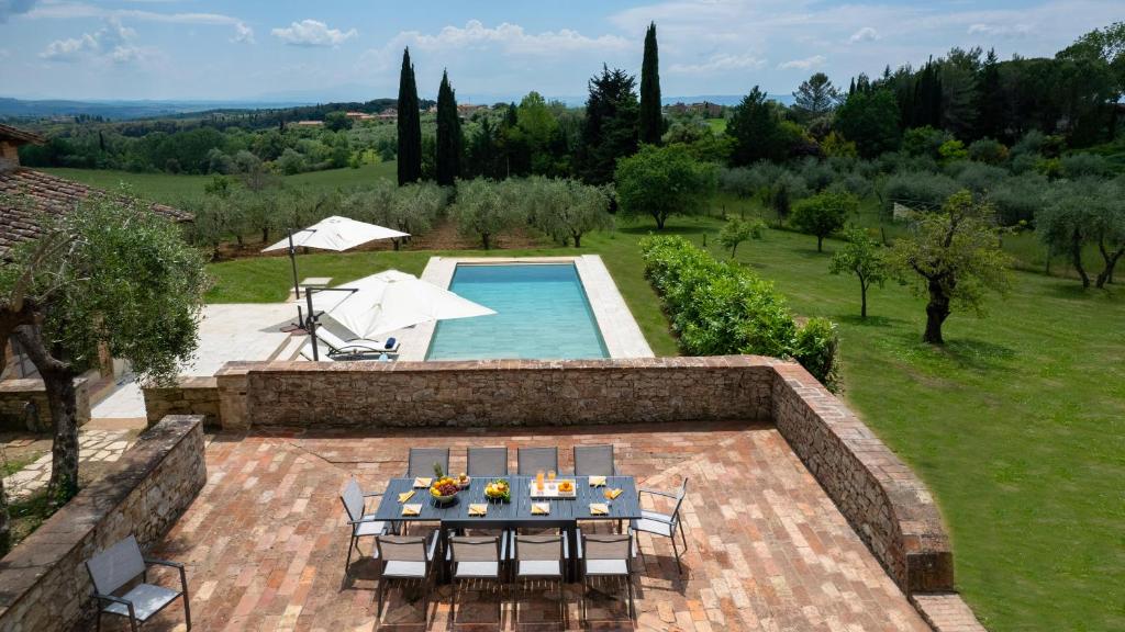 un patio extérieur avec une table et des chaises ainsi qu'une piscine dans l'établissement TERRA DI SIENA 14, Emma Villas, à Castelnuovo Berardenga