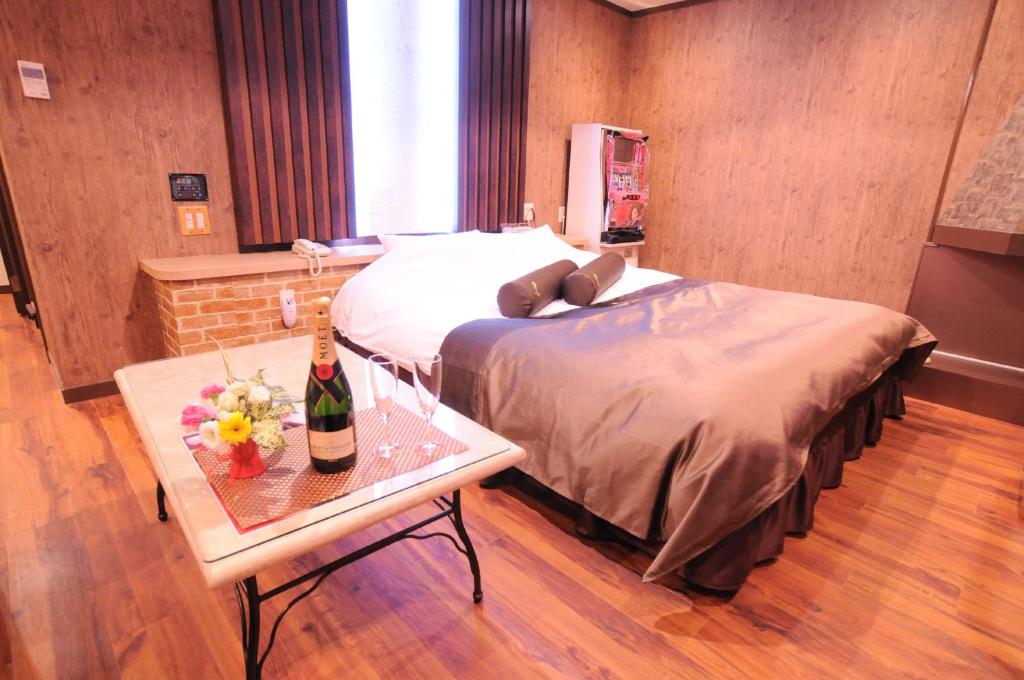 - une chambre avec un lit et une table avec une bouteille de vin dans l'établissement STAR RESORT Will, à Morioka