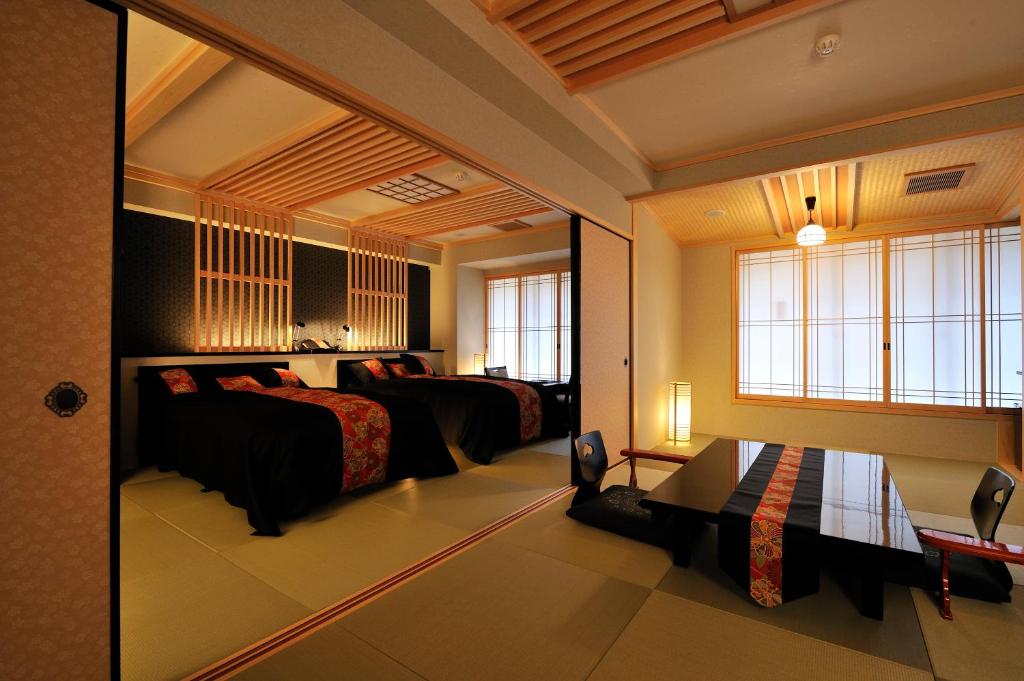 Cette grande chambre comprend deux lits et une fenêtre. dans l'établissement Matsui Honkan, à Kyoto