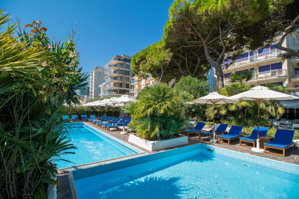 une piscine avec des chaises bleues et des parasols dans l'établissement Hotel Majestic, à Lido di Jesolo