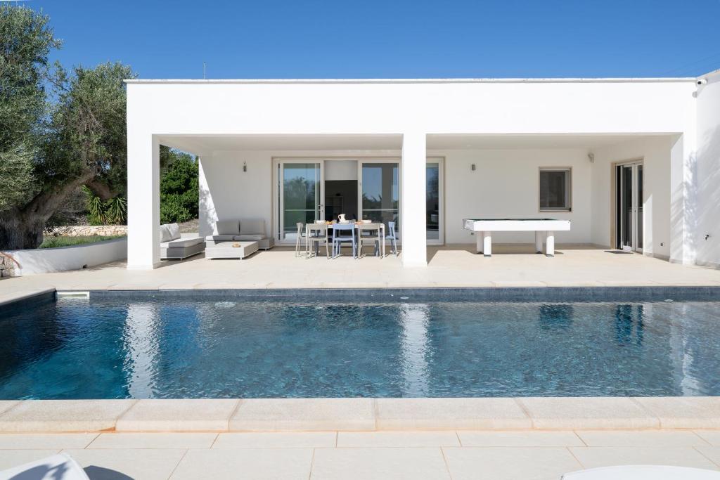 - une piscine en face d'une maison avec une table dans l'établissement Casa Mathilde by Bianco Puglia Vacanze, à San Vito dei Normanni