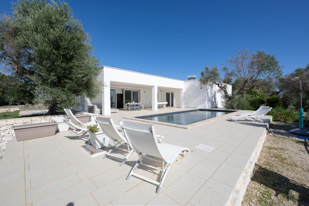 un groupe de chaises assises à côté d'une piscine dans l'établissement Casa Mathilde by Bianco Puglia Vacanze, à San Vito dei Normanni