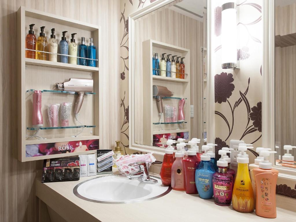 une salle de bain avec un lavabo, un miroir et quelques bouteilles dans l'établissement Hotel Rose (Adult Only), à Gifu