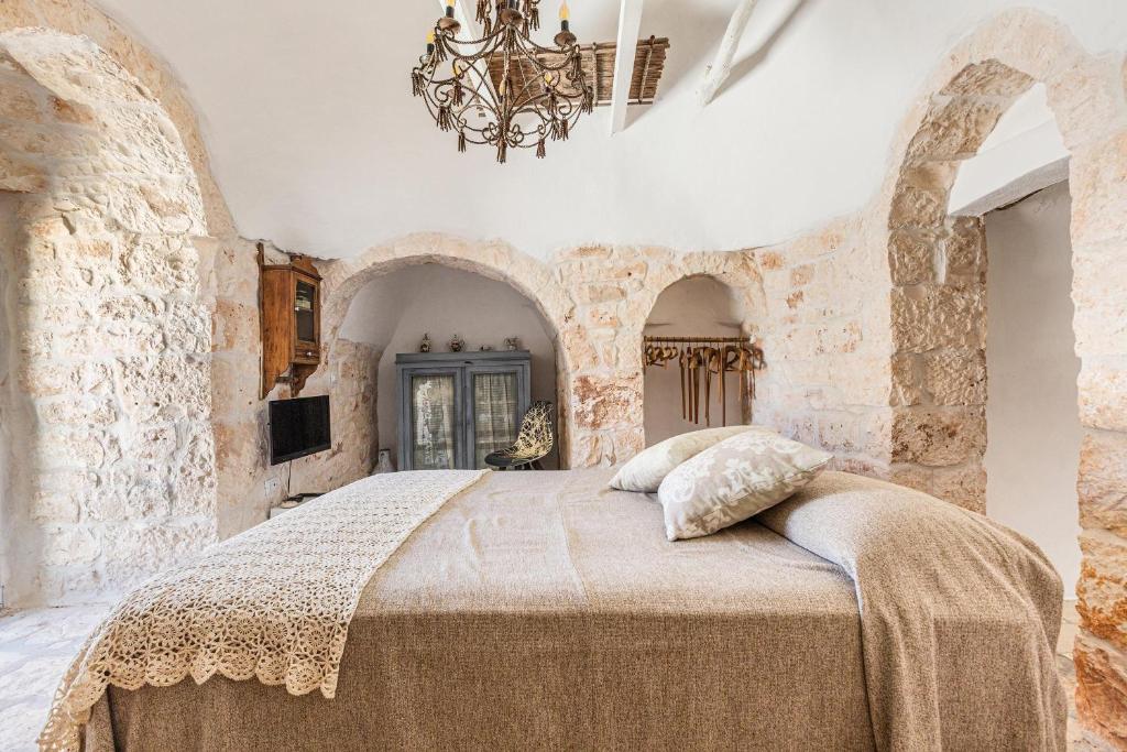 une chambre avec un grand lit dans un mur de pierre dans l'établissement O` Trullo Mio by Perle di Puglia, à Ostuni