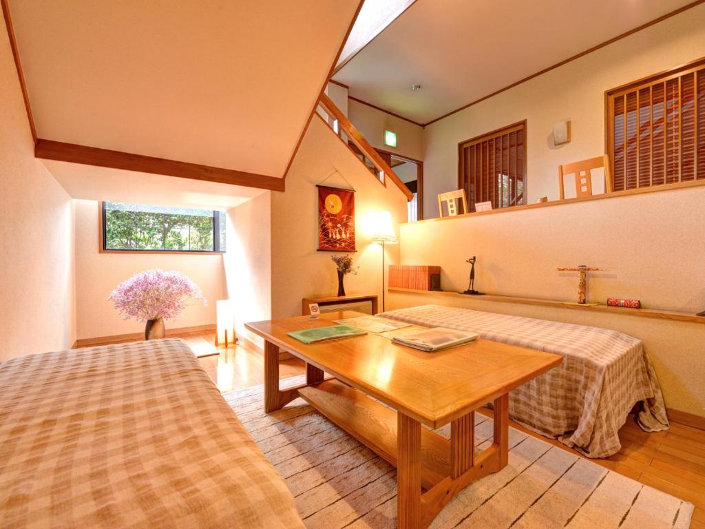 Cette chambre comprend 2 lits et une table en bois. dans l'établissement Yufuin Yamaboushi, à Yufu