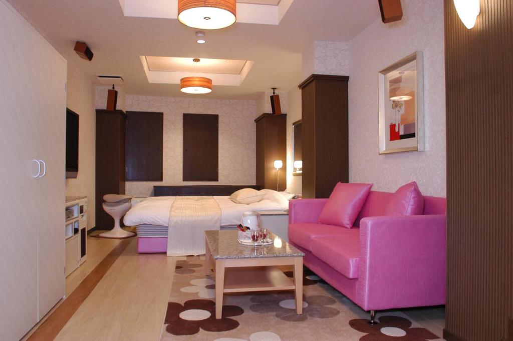 un salon avec un canapé violet et un lit dans l'établissement Hotel Antoinette -SPA RESORT- AdultOnly, à Okazaki