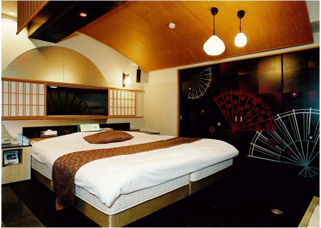 une chambre avec un grand lit avec des œuvres d'art sur le mur dans l'établissement Hotel Antoinette -SPA RESORT- AdultOnly, à Okazaki