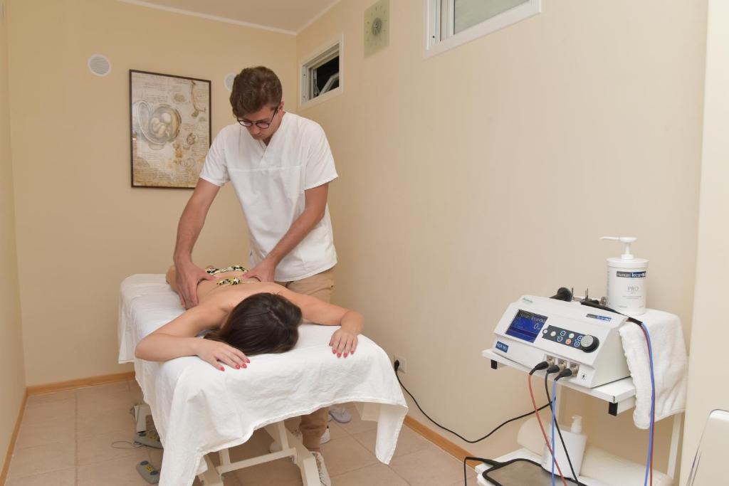 une femme allongée sur un lit d'hôpital avec un médecin dans l'établissement Hotel San Valentino Terme, à Ischia