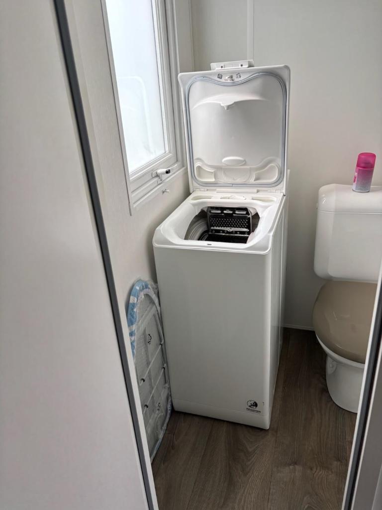 - un petit réfrigérateur blanc dans une salle de bains à côté des toilettes dans l'établissement Mh 3 ch - 1 sdb - terrasse couverte - kerlann, à Pont-Aven