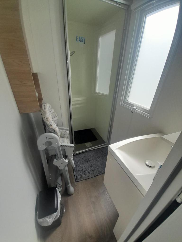 une salle de bains avec douche, lavabo et miroir dans l'établissement Mh 3 ch - 1 sdb - terrasse couverte - kerlann, à Pont-Aven