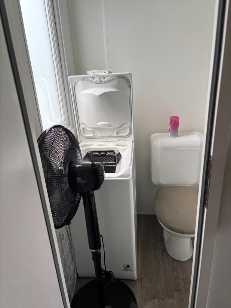 La petite salle de bains est pourvue de toilettes et d'un ventilateur. dans l'établissement Mh 3 ch - 1 sdb - terrasse couverte - kerlann, à Pont-Aven