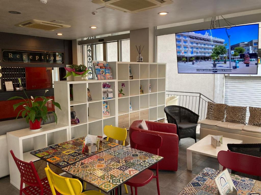un restaurant avec une table, des chaises et une télévision dans l'établissement Hotel Panorama, à Lido di Jesolo