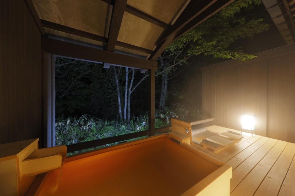 une pièce avec une table et une grande fenêtre dans l'établissement Miyama Ouan Kyoritsu Resort, à Takayama
