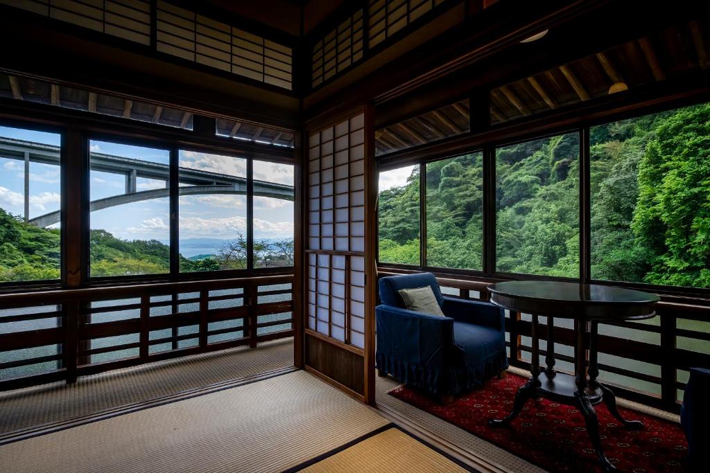 une pièce avec une chaise, une table et des fenêtres dans l'établissement Okamotoya, à Beppu