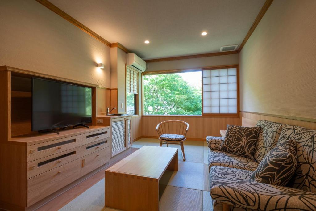 un salon avec un canapé et une télévision à écran plat dans l'établissement Miyama Ouan Kyoritsu Resort, à Takayama