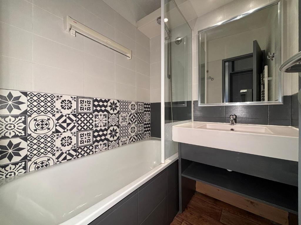 une salle de bain avec une baignoire, un lavabo et un miroir dans l'établissement Résidence Britania Clés Blanches, à La Tania