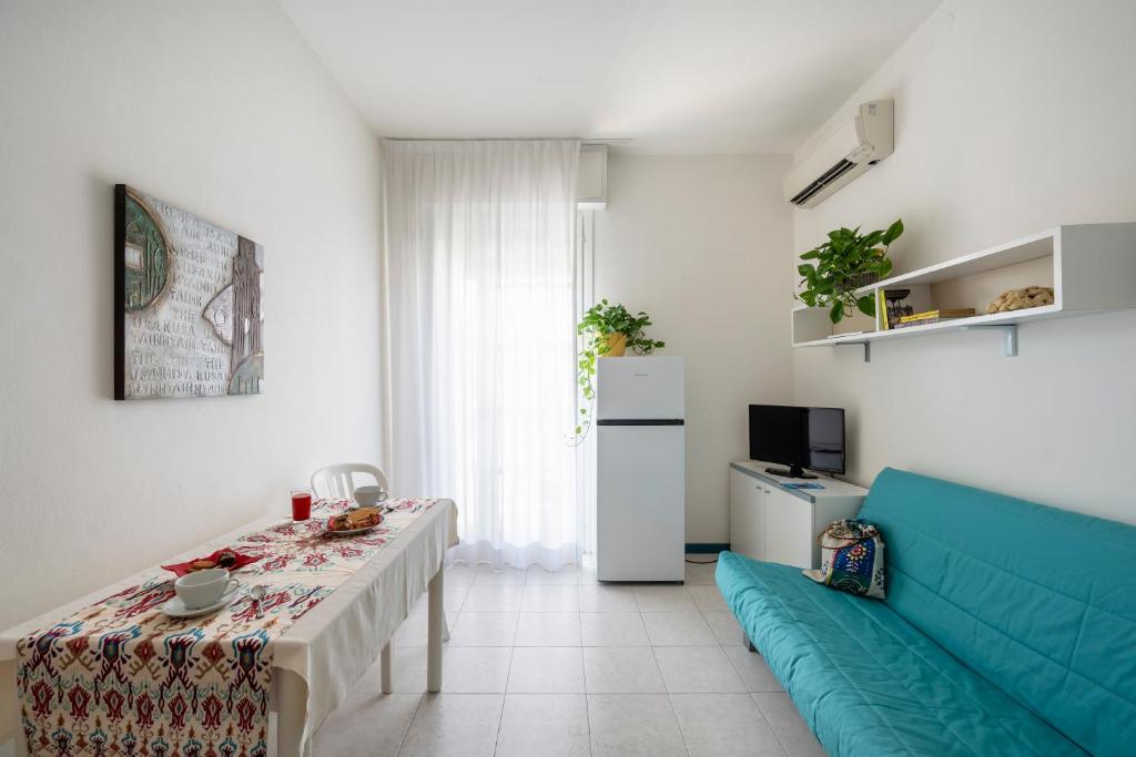 un salon avec une table et un canapé bleu dans l'établissement Aparthotel Pineda, à Bibione 80 autres photos