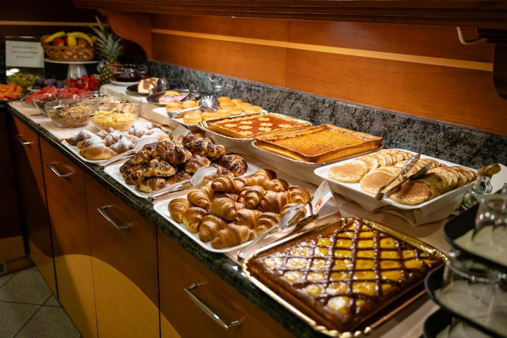 un buffet avec de nombreux types de pains et de viennoiseries dans l'établissement Aparthotel Pineda, à Bibione