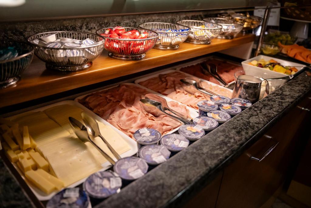 un buffet avec de la viande et d'autres aliments sur un comptoir dans l'établissement Aparthotel Pineda, à Bibione