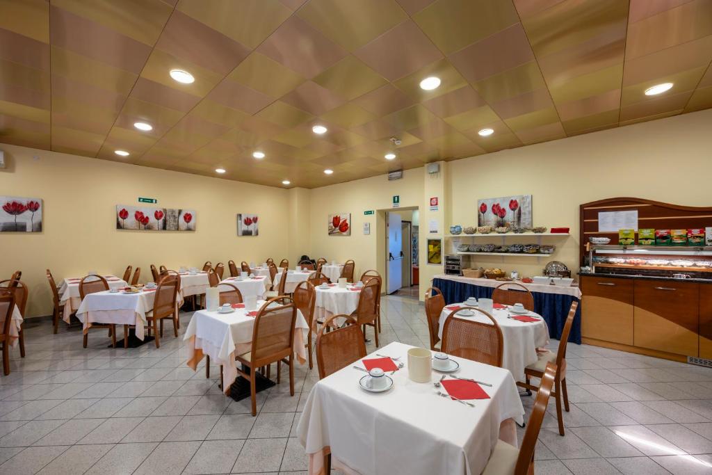 un restaurant avec des tables et des chaises avec une nappe blanche dans l'établissement Aparthotel Pineda, à Bibione