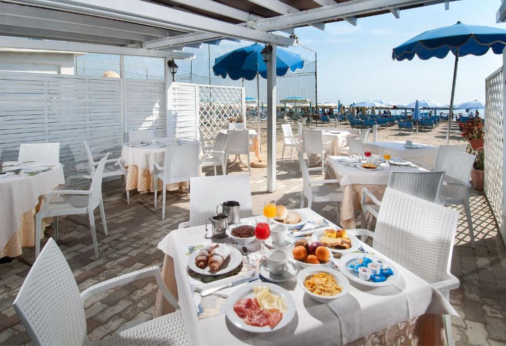 - une table avec des assiettes de nourriture au-dessus de la plage dans l'établissement Hotel Souvenir, à Lido di Savio
