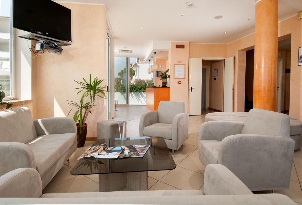 - un salon avec des canapés, des chaises et une télévision dans l'établissement Hotel Souvenir, à Lido di Savio