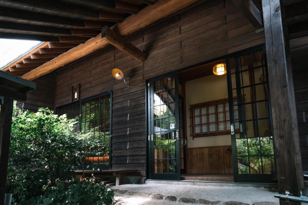 Cette maison en bois dispose d'une porte et de fenêtres en bois. dans l'établissement 山荘 紗羅樹 Syaranoki, à Yufu