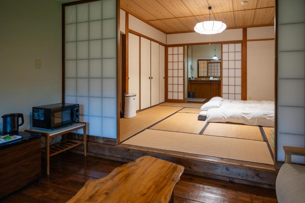 Cette chambre comprend un lit, une télévision et un miroir. dans l'établissement 山荘 紗羅樹 Syaranoki, à Yufu