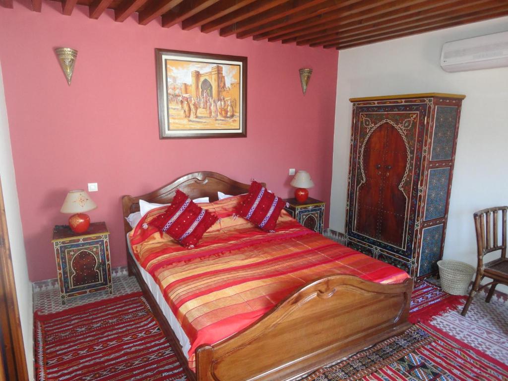 une chambre avec un grand lit aux murs rouges dans l'établissement Dar Yanis, à Rabat
