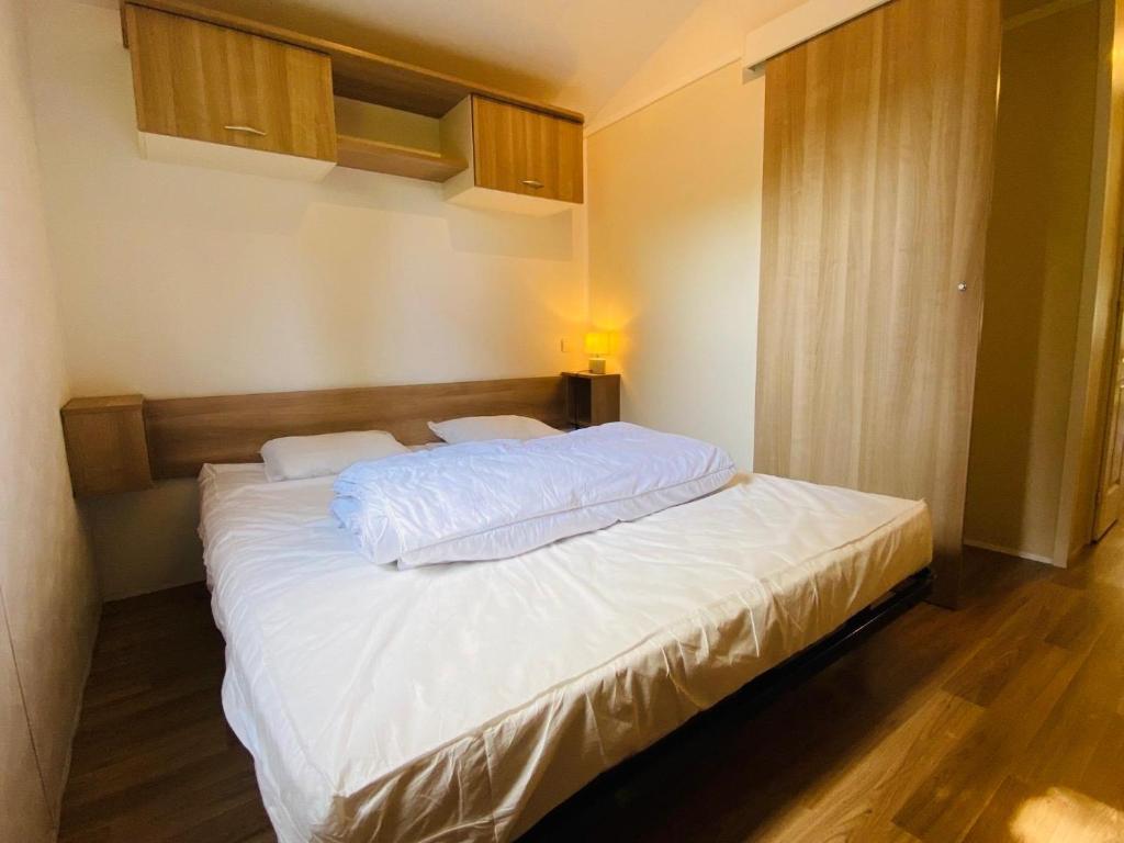 une chambre avec un grand lit avec des draps blancs dans l'établissement Carnac - Mobil Home - 5 pers - 2 ch - Camping Moulin de Kermaux 4* - Piscine, à Carnac 22 autres photos