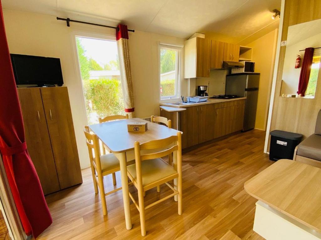 une cuisine avec une table et des chaises dans une pièce dans l'établissement Carnac - Mobil Home - 5 pers - 2 ch - Camping Moulin de Kermaux 4* - Piscine, à Carnac